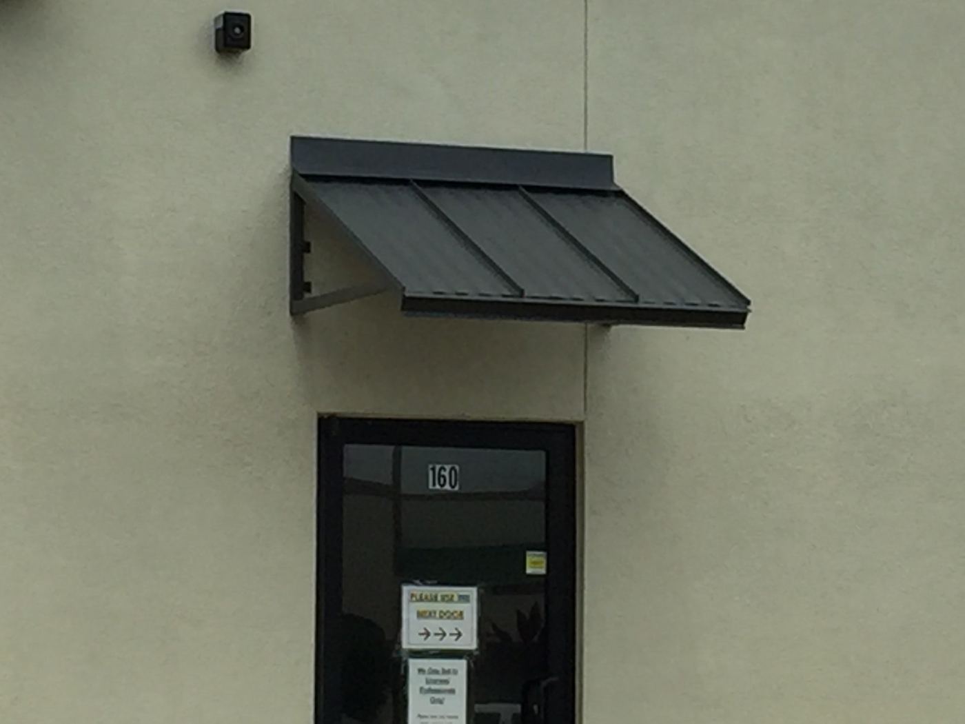 Dark metal awning with three panels over an office door