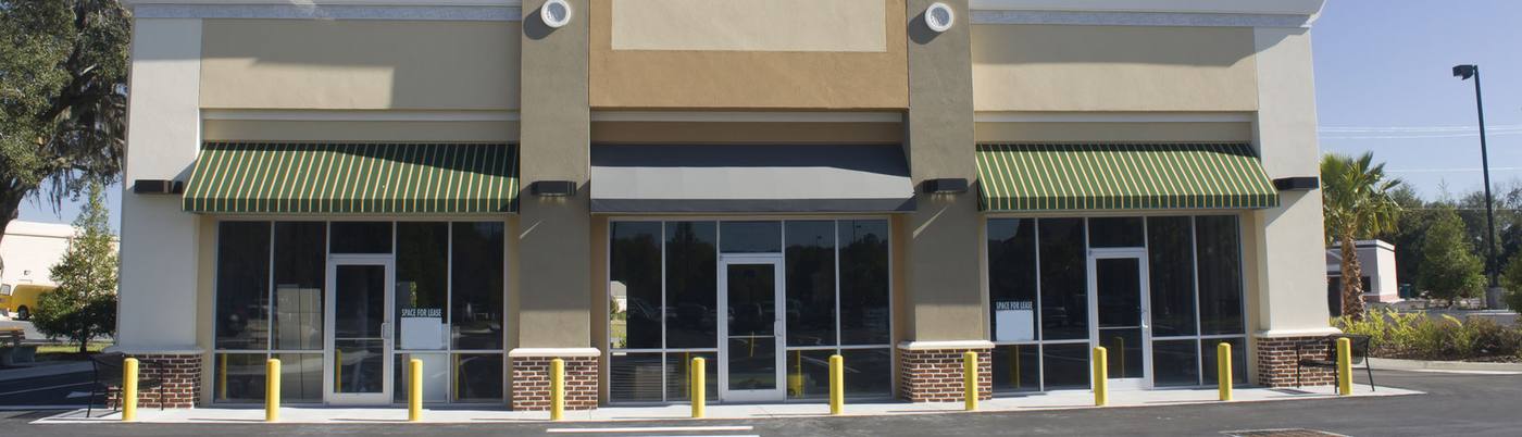 Storefronts with green striped and black awnings and yellow bollards